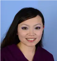 Smiling woman with long dark hair and purple eyeshadow, wearing a purple top, against a light blue background. The image conveys a friendly and professional demeanor, suitable for a healthcare or beauty-related context.