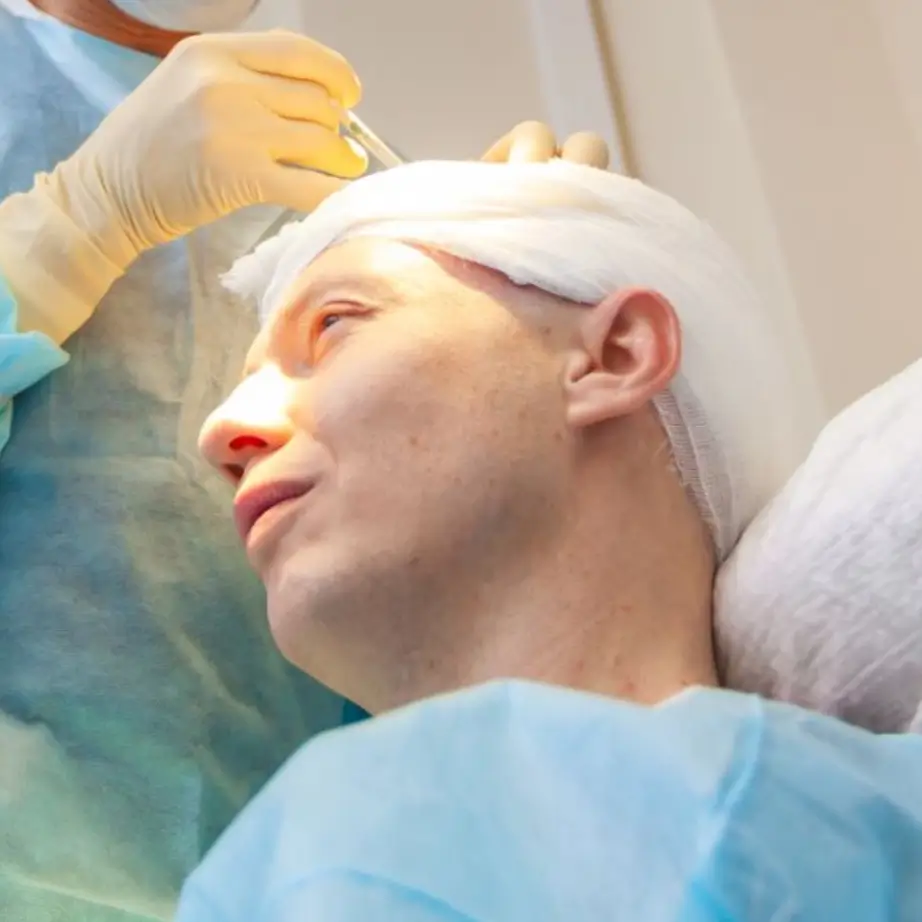 A medical professional performs a cosmetic procedure on a patient in a clinical setting. The patient, wearing a surgical gown, appears relaxed while the practitioner, dressed in sterile gloves and surgical attire, administers treatment. The image highlights the careful and precise nature of cosmetic surgery, emphasizing the importance of safety and professionalism in medical aesthetics.
