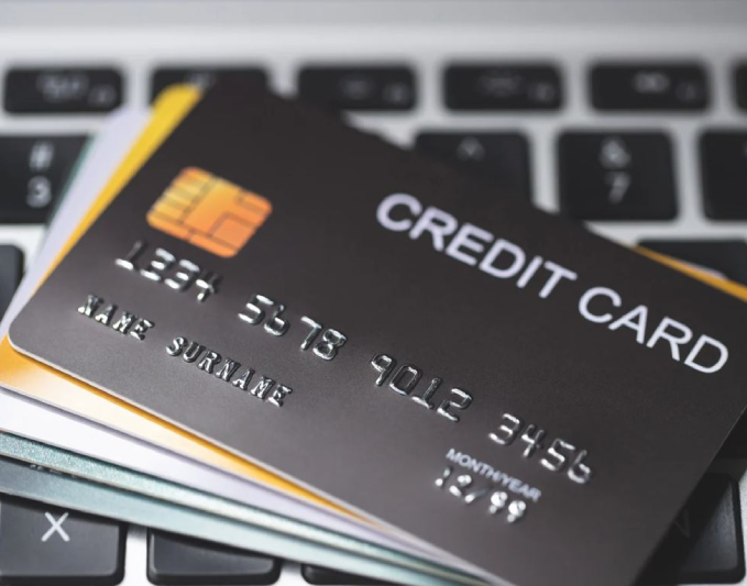 Close-up of a black credit card with embossed numbers and a chip, resting on a laptop keyboard. The image highlights the convenience of online transactions and digital payments, showcasing the importance of secure financial tools for consumers. Ideal for articles related to personal finance, e-commerce, or digital banking, this visual emphasizes the integration of technology and finance in everyday life.
